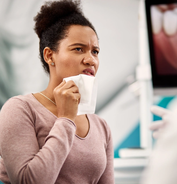 Woman in purple shirt holding white cup in modern dental office setting.