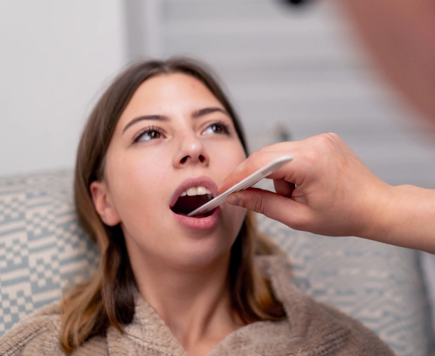 Patient receiving oral examination with tongue depressor at dental clinic