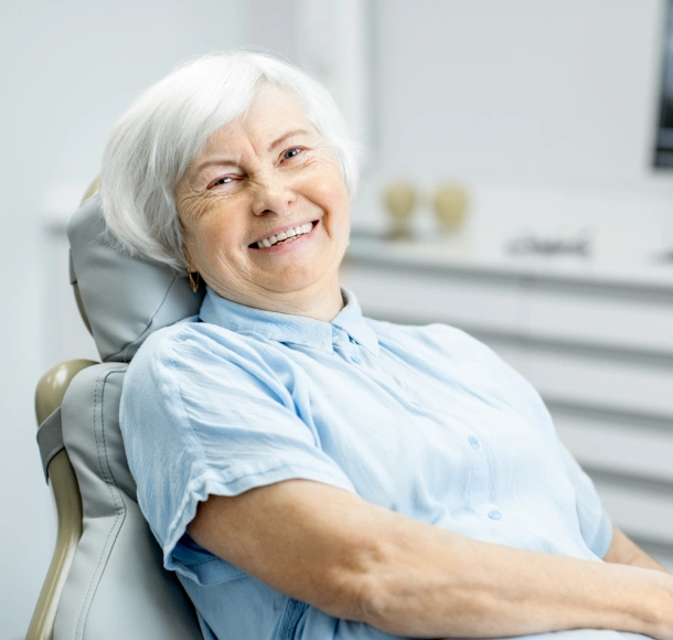 Smiling senior woman in dental chair at Highbridge Dental Associates office.