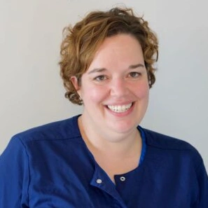 Smiling dental professional in blue scrubs against white background, headshot for Highbridge Dental Associates.